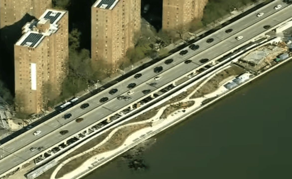 Aerial view of waterfront roadway with adjacent buildings.
